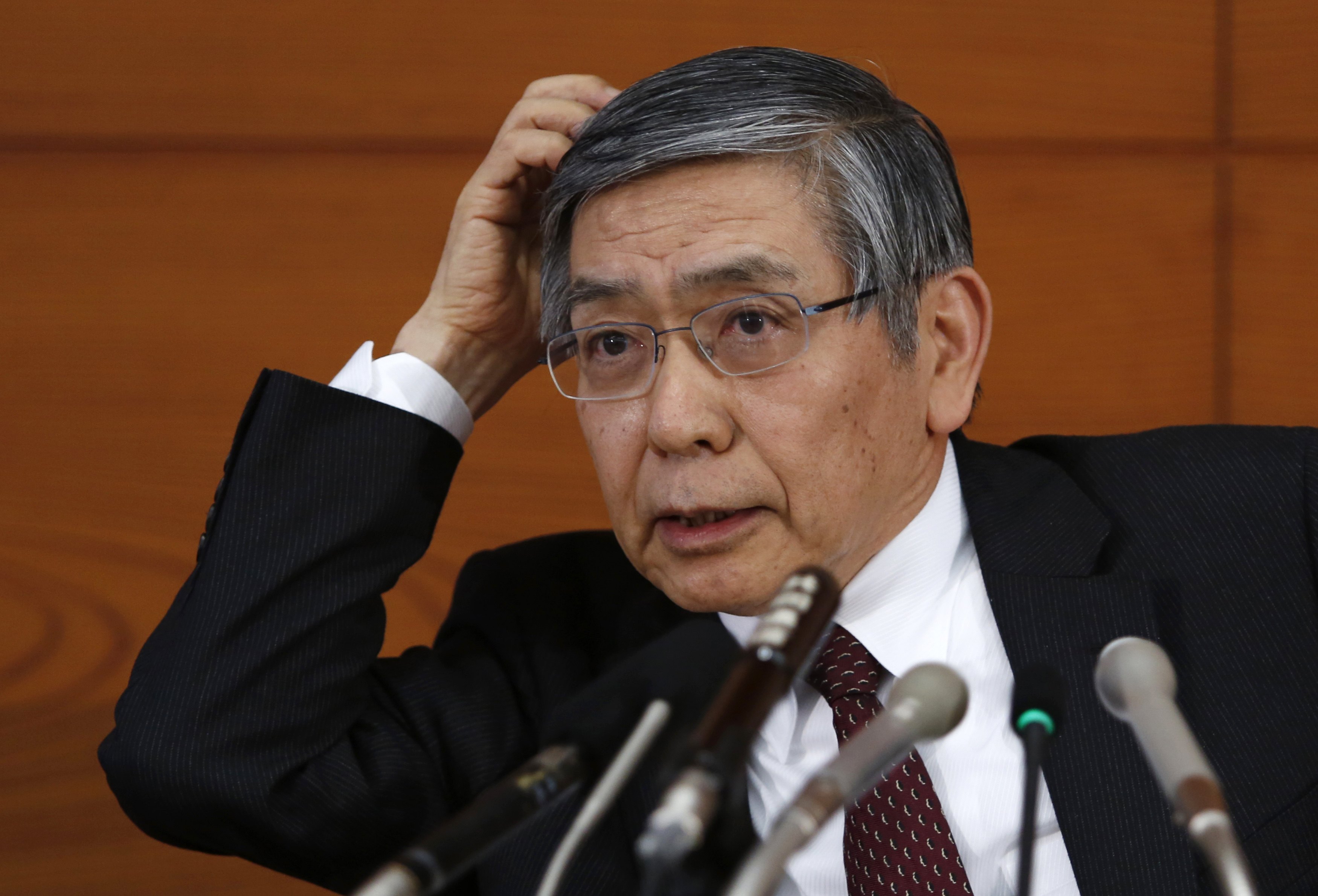 Bank of Japan Governor Kuroda scratches his head as he listens to questions from a reporter during a news conference in Tokyo