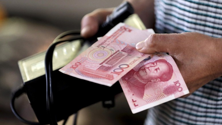 File photo of a customer holding 100 Yuan notes at a market in Beijing
